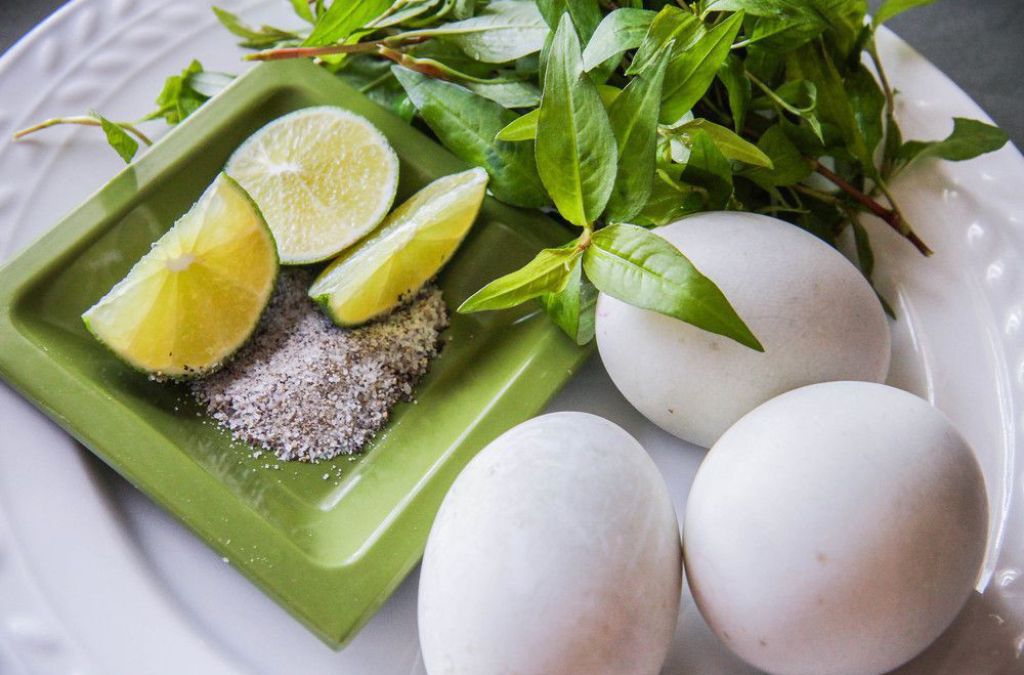 Trứng vịt lộn ăn kèm rau răm, chanh và muối tiêu