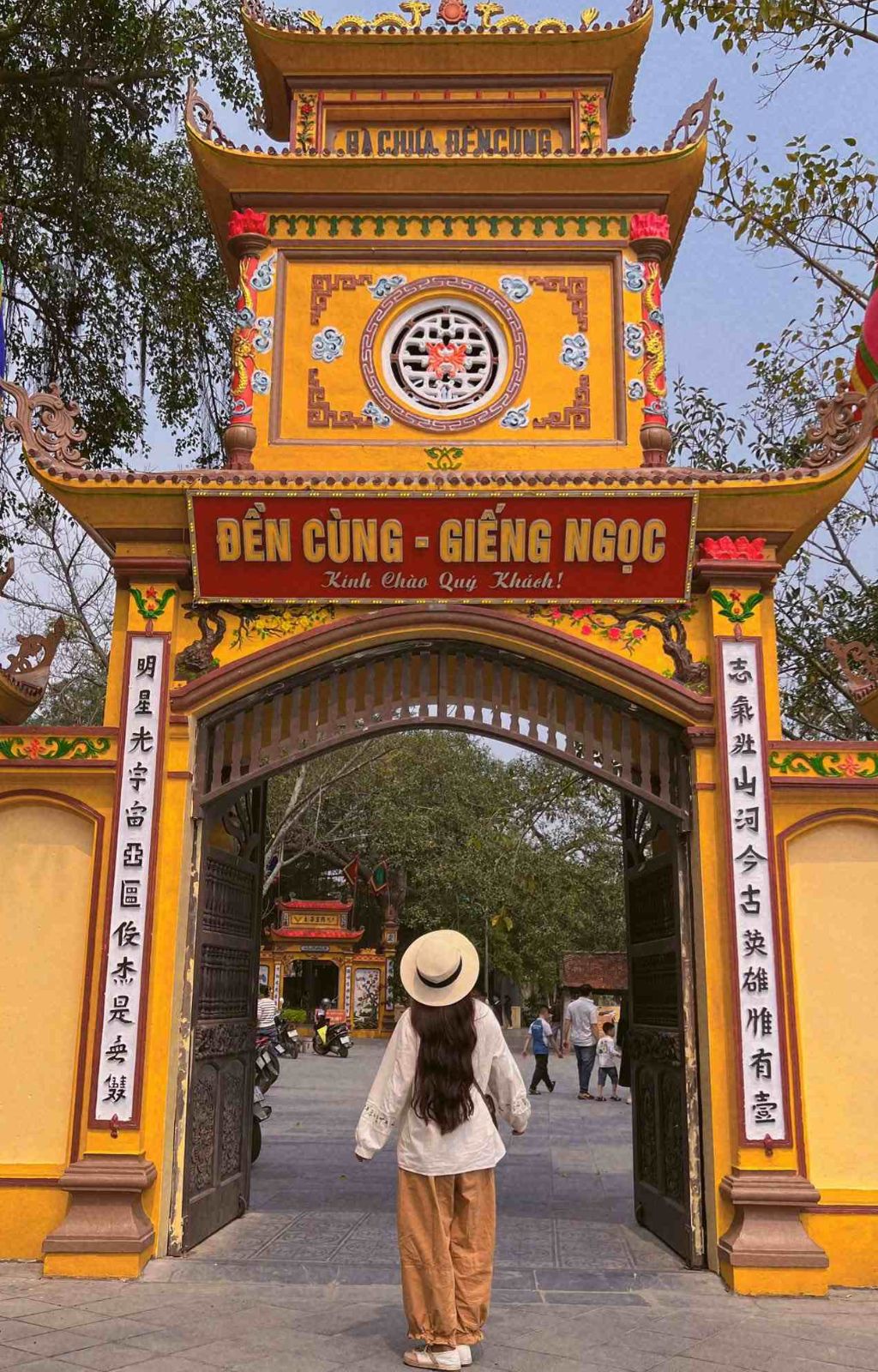  Người tham quan đứng trước cổng Đền Cùng – Giếng Ngọc màu vàng với mái cong và câu đối