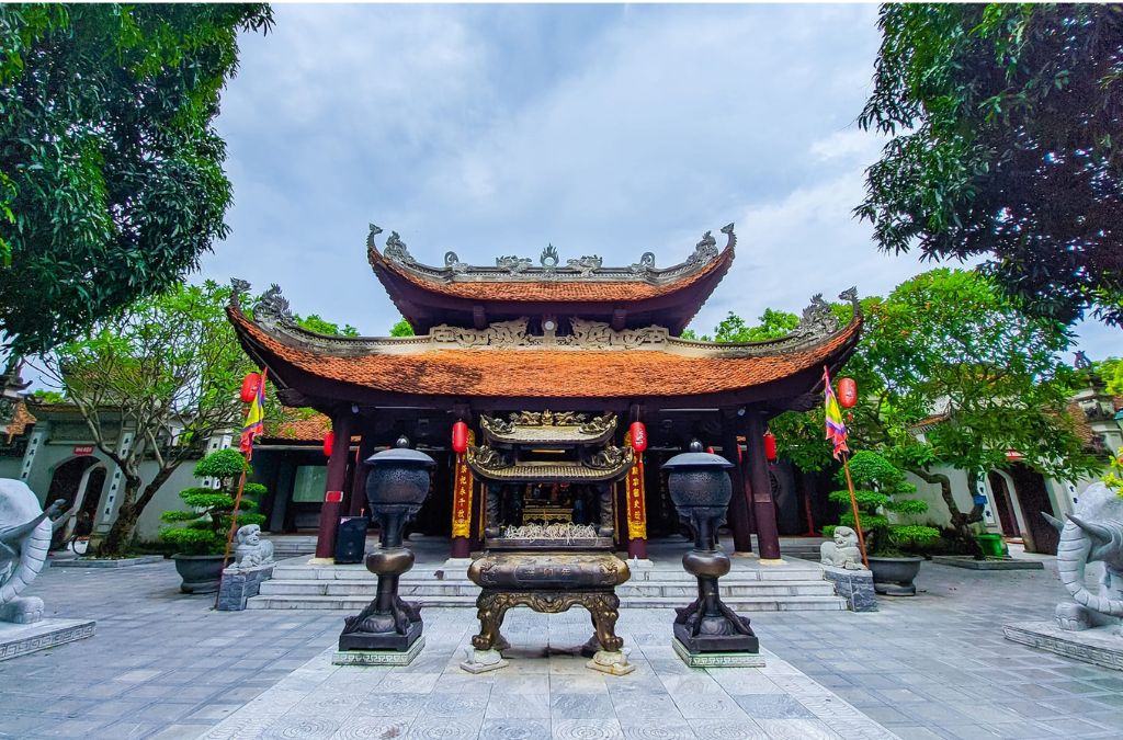 Cổng Đền Đô với mái ngói cong, lư hương và tượng đá hai bên lối vào