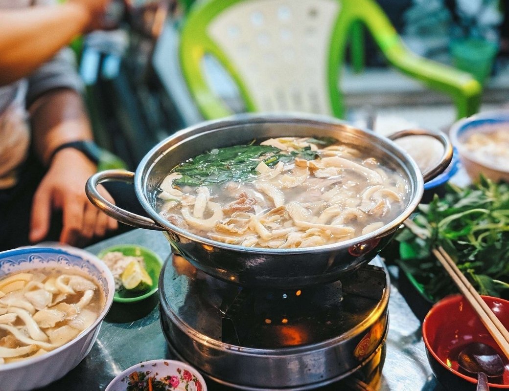 Nồi lẩu gà lá é nóng cùng thịt gà và lá é xanh
