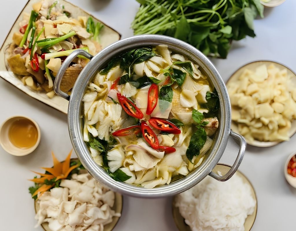 Nồi lẩu gà lá é nóng hổi với thịt gà, lá é, măng và nấm.