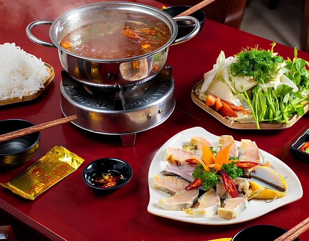 Nồi lẩu cá tầm nóng hổi với cá tầm, măng, nấm và rau Đà Lạt.