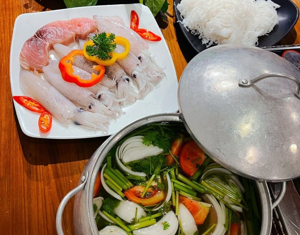 Nồi lẩu mực Đại Lãnh với mực tươi, rau và nước dùng chua cay.