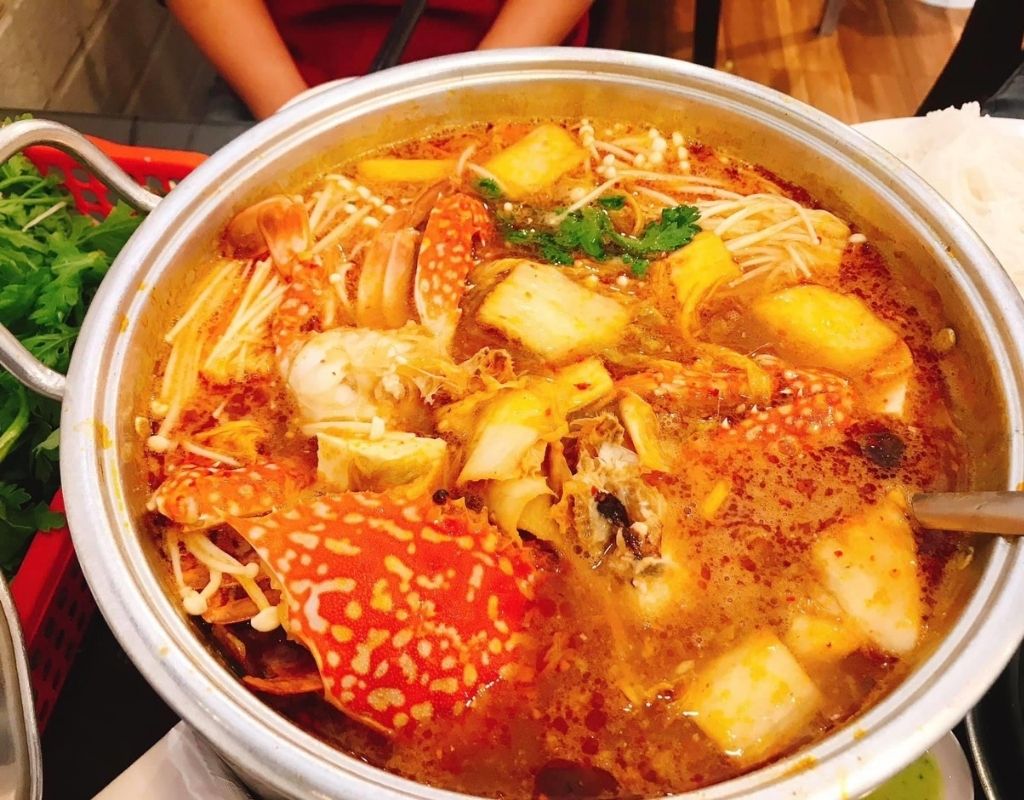 Nồi lẩu ghẹ kim chi với ghẹ tươi, kim chi, nấm và rau.
