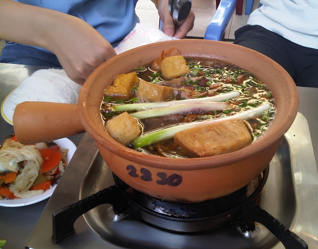 Lẩu dê tay cầm với thịt dê, khoai môn, củ sen và tàu hũ ky.