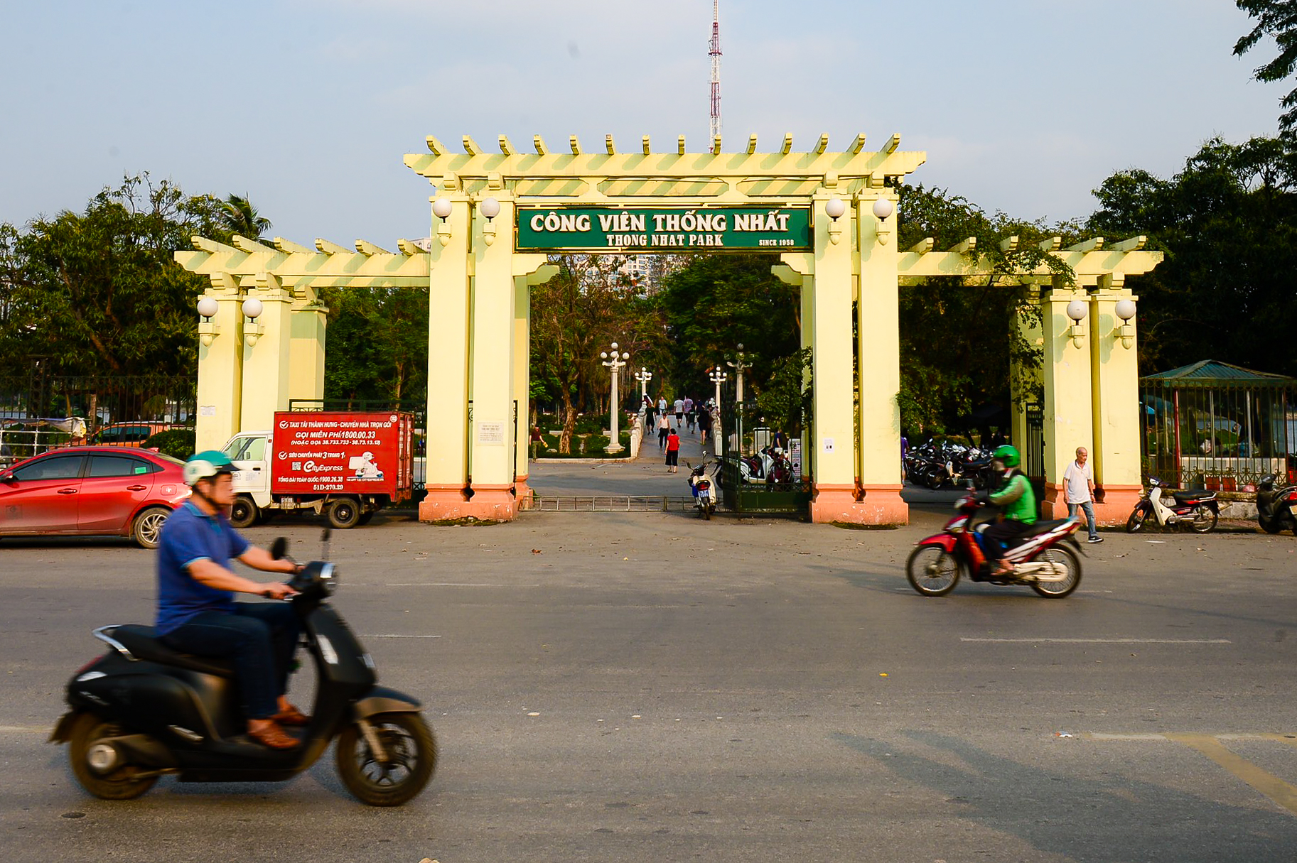 Cổng chính Công viên Thống Nhất Hà Nội với kiến trúc màu vàng nổi bật và hàng cây xanh phía trong.