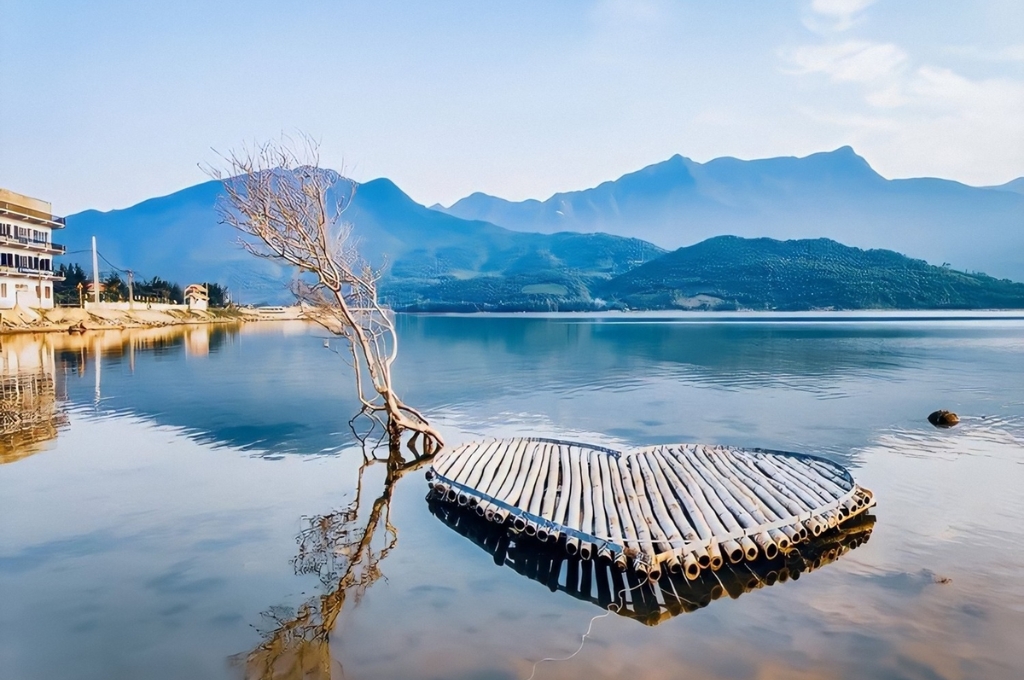 Cảnh sắc thơ mộng với chiếc bè gỗ hình trái tim và khung núi non phản chiếu trên mặt nước Đầm Lập An Huế