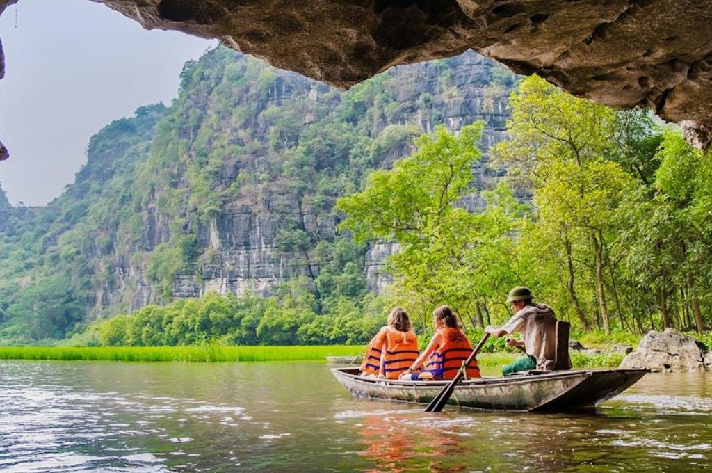 Thuyền nan chở khách tham quan Tràng An giữa núi đá vôi và dòng nước xanh ở Ninh Bình