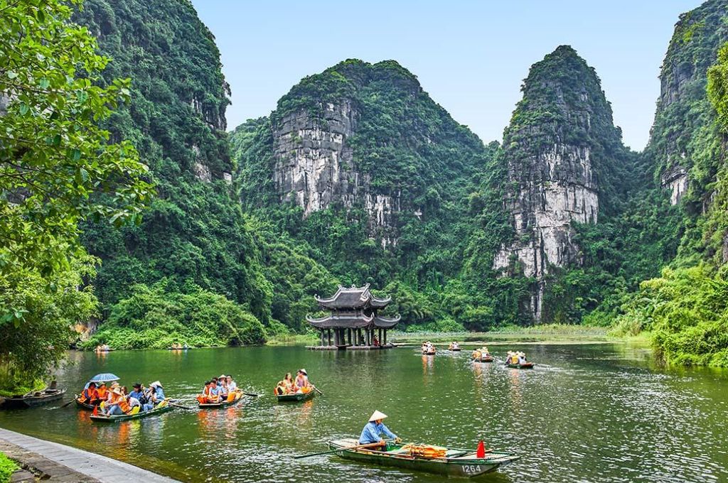 Thuyền nan trên hồ nước giữa những dãy núi đá vôi và cây xanh tại Ninh Bình