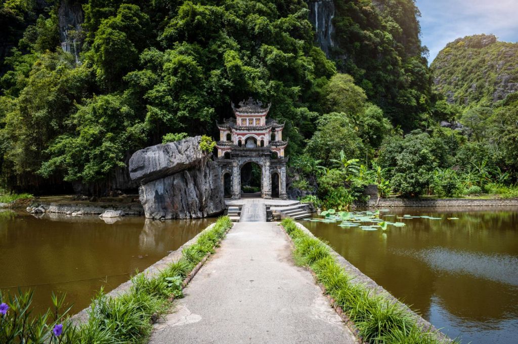 Cổng tam quan chùa Bích Động Ninh Bình với cầu đá và hồ nước phía trước
