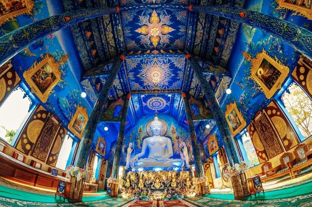 Không gian chánh điện Wat Rong Suea Ten - Chùa Xanh (Chiang Rai) gây ấn tượng với tượng Phật ngọc trắng muốt nổi bật trên nền bích họa xanh lam.