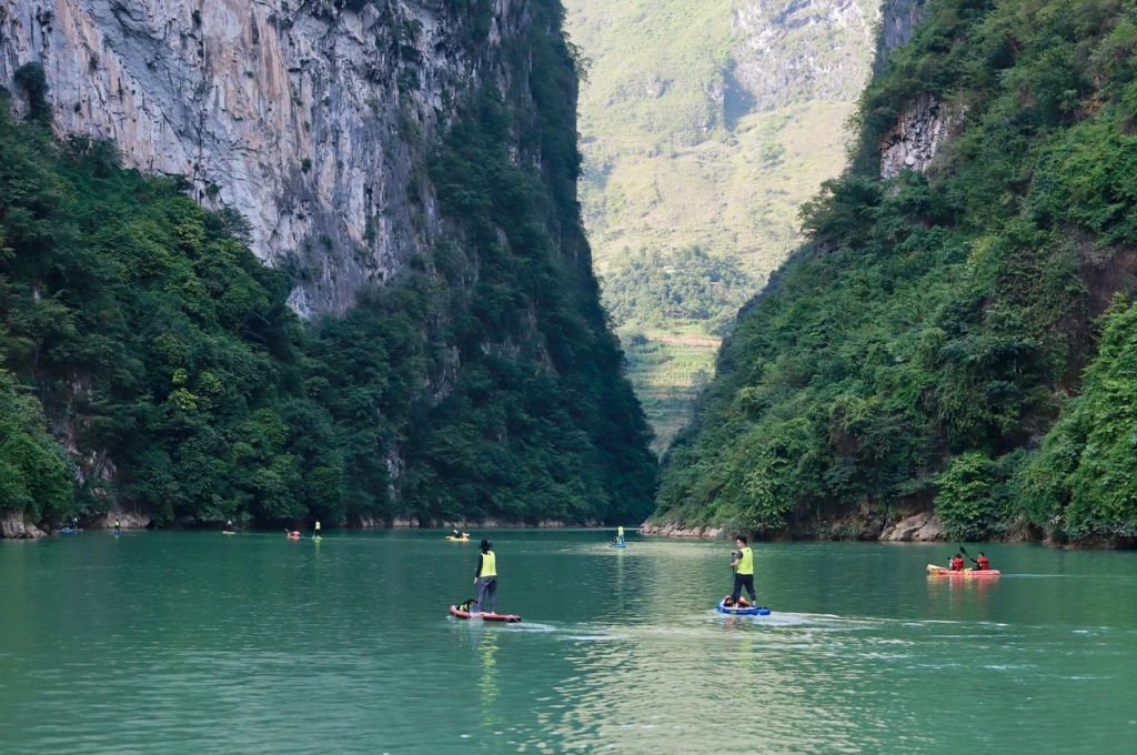 Du khách tham gia chèo SUP và kayak trên sông Nho Quế giữa những vách đá cao tại hẻm Tu Sản