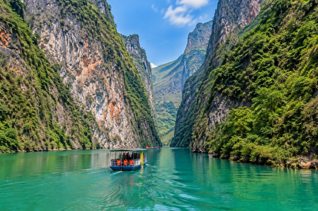 Thuyền tham quan di chuyển trên dòng sông Nho Quế xanh ngọc giữa những vách núi đá cao tại hẻm Tu Sản.