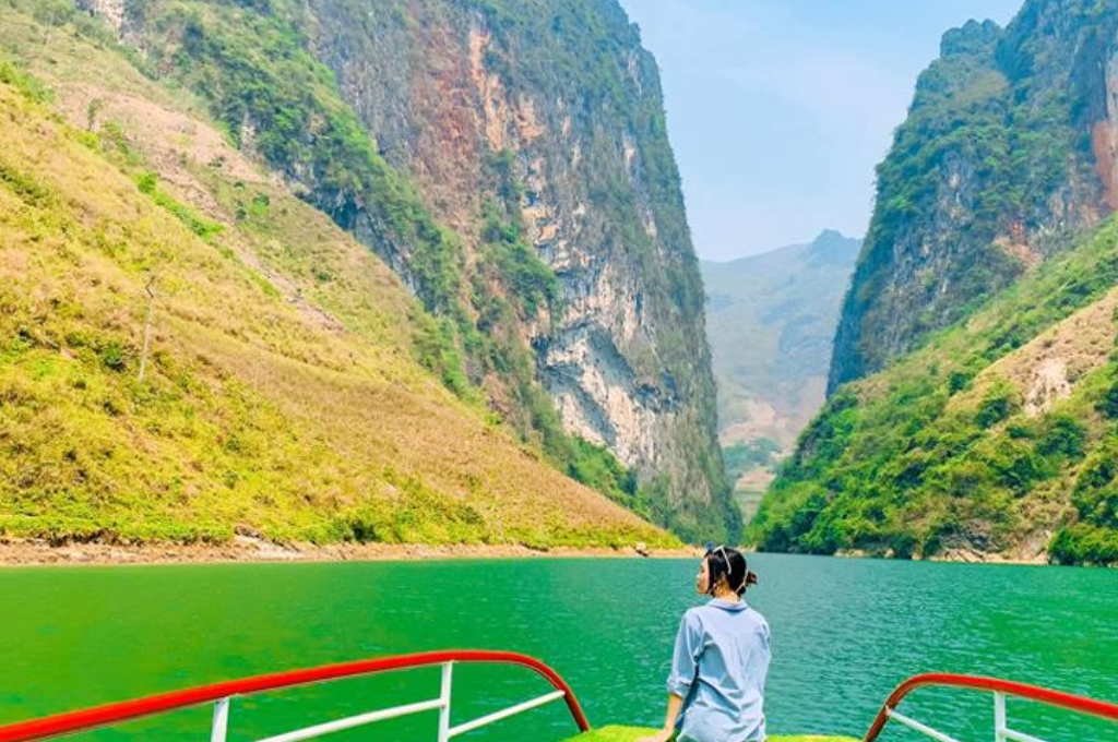 Khách tham quan ngồi trên thuyền ngắm dòng sông Nho Quế dưới ánh nắng giữa hai vách đá hẻm Tu Sản.