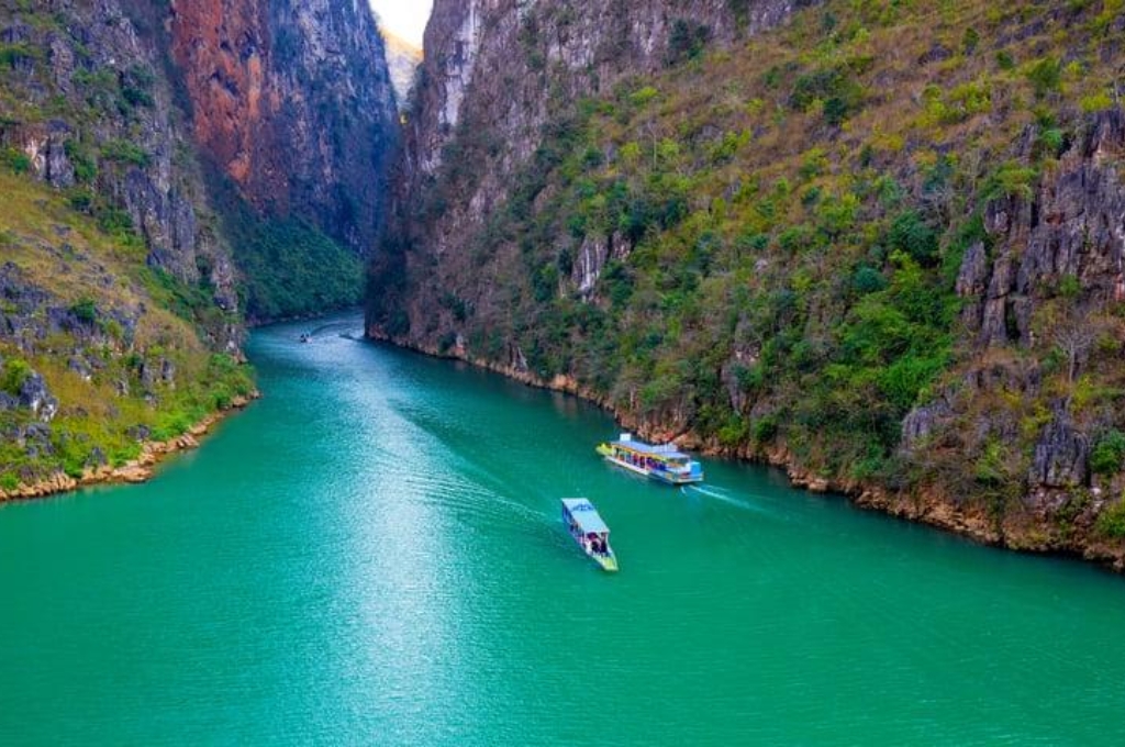 Thuyền du lịch di chuyển giữa hai vách núi đá dựng đứng tại hẻm Tu Sản trên sông Nho Quế