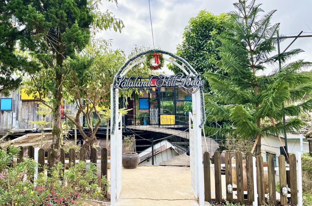 Cổng vào Lalaland Homestay giữa khu vườn nhiều cây xanh