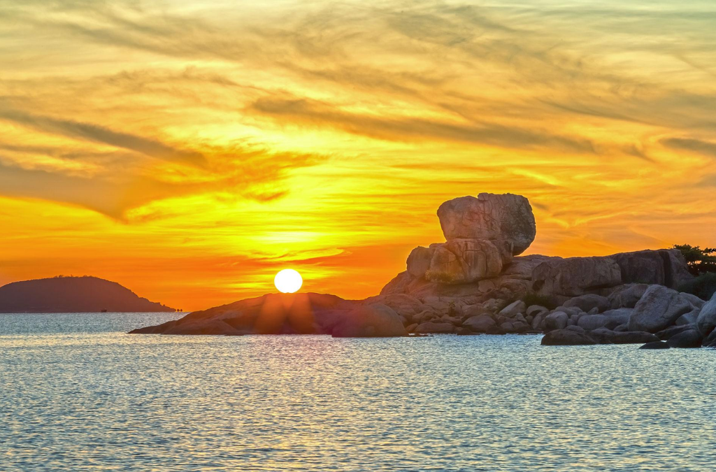 Bình minh trên Hòn Chồng Nha Trang với mặt trời đỏ cam, các khối đá granite và mặt biển lấp lánh.