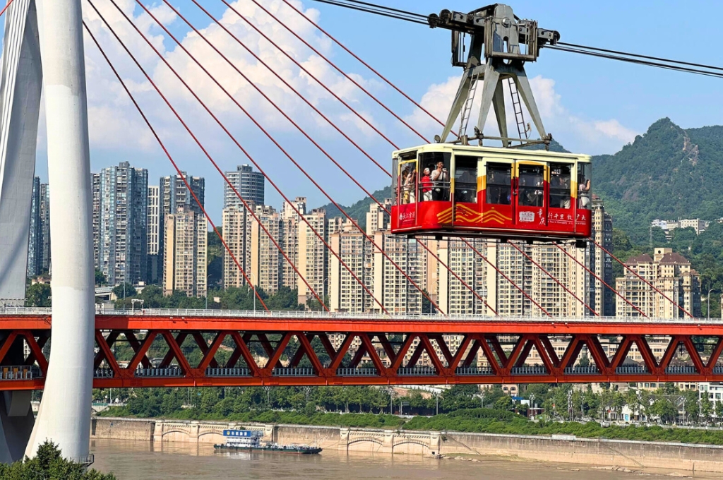 Cáp treo sông Dương Tử (Trường Giang) với cabin màu đỏ di chuyển trên cao giữa thành phố Trùng Khánh.