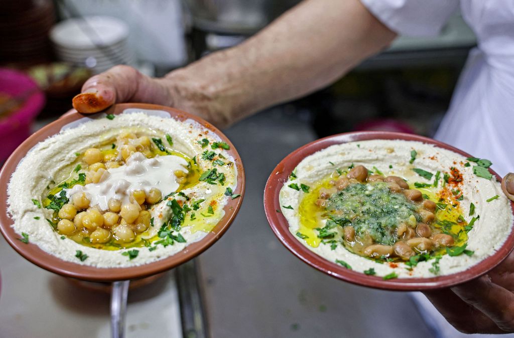 Hai đĩa Hummus phủ đậu gà, dầu olive và rau thơm