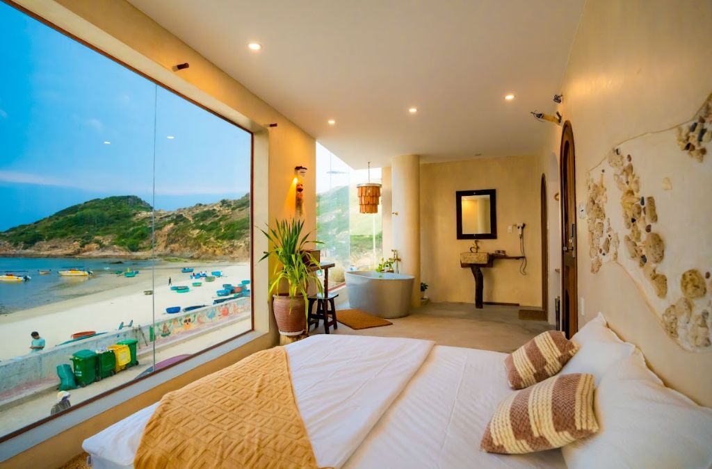 Phòng nghỉ view biển với cửa kính lớn hướng ra bãi thuyền làng chài Nhơn Lý