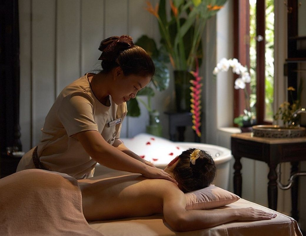 Kỹ thuật viên thực hiện massage cổ truyền Lào tại spa.