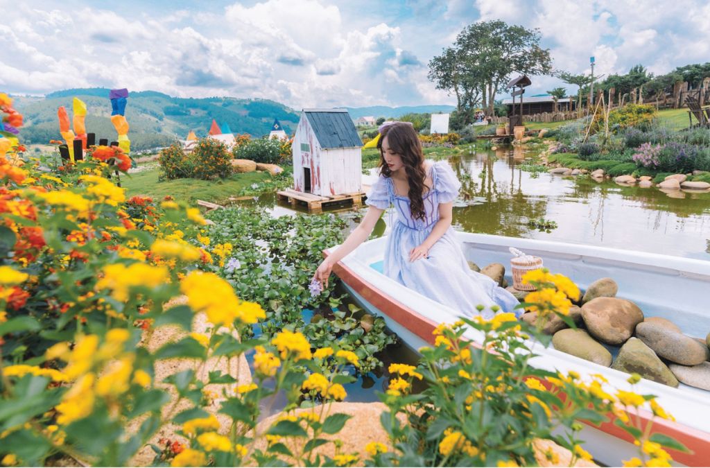 Cô gái chụp ảnh trên thuyền giữa vườn hoa và hồ nước Mongo Land