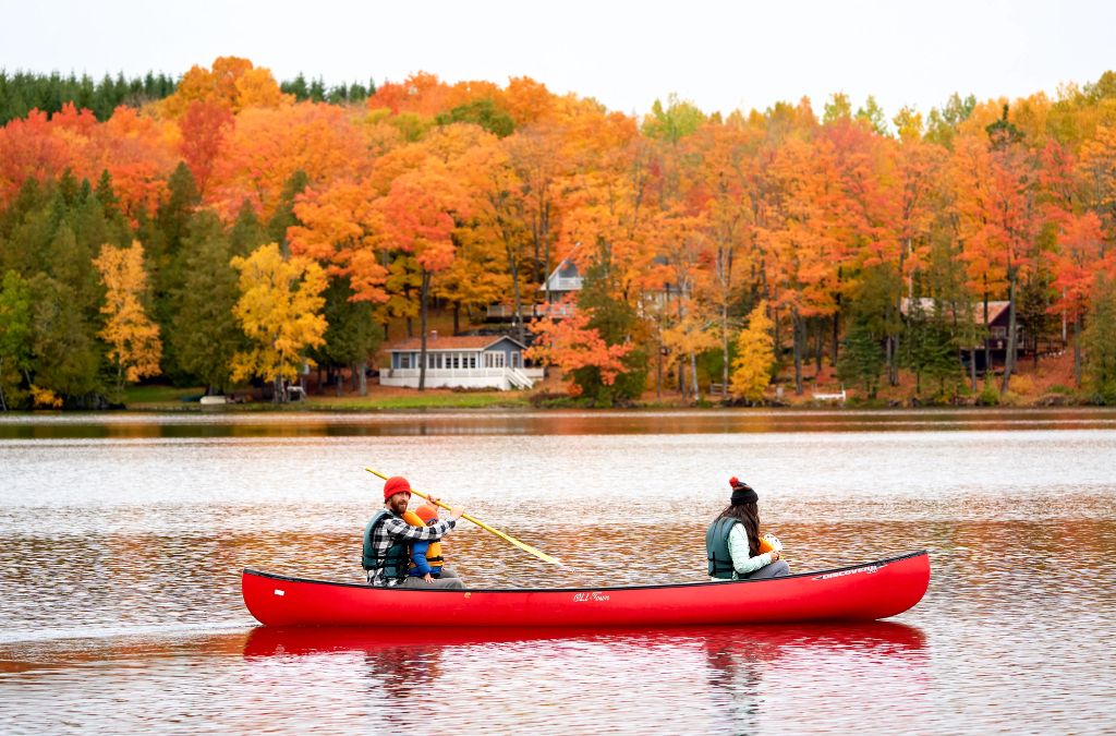 Chèo canoe giữa hồ và rừng phong mùa thu Canada