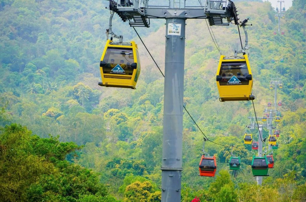 Các cabin cáp treo màu vàng di chuyển phía trên rừng cây trên núi Cấm