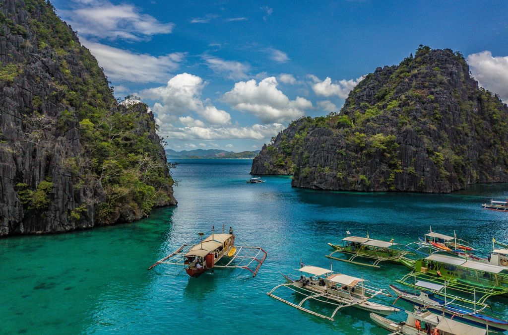 Thuyền trên vùng nước xanh giữa vách đá gần Kayangan Lake