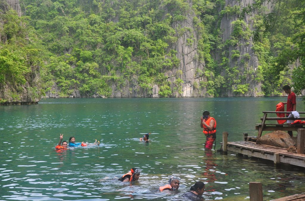 Người bơi trong hồ nước xanh giữa núi đá tại Coron