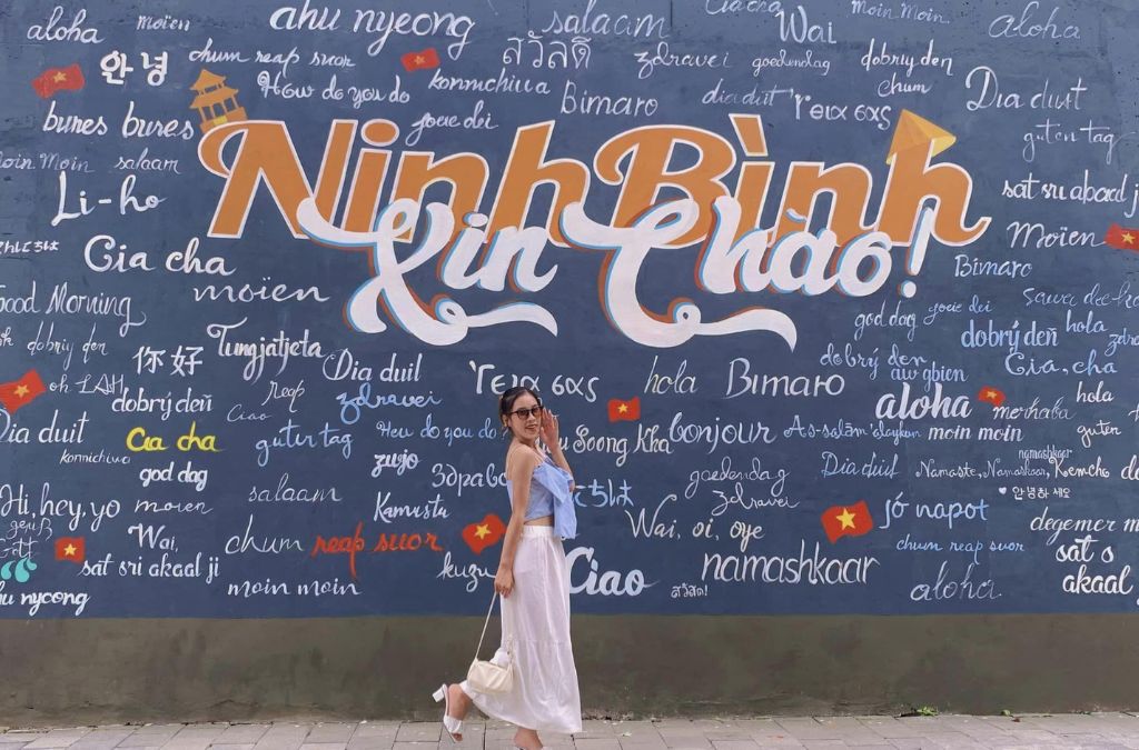 Cô gái chụp ảnh trước bức tường “Ninh Bình xin chào”