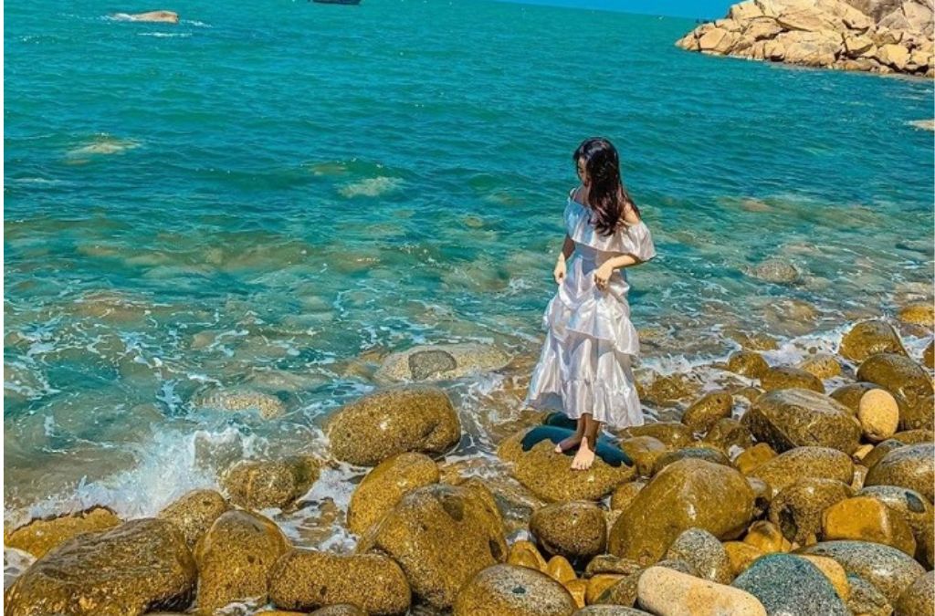 Một phụ nữ đứng trên bãi đá tròn bên biển tại Ghềnh Ráng Tiên Sa