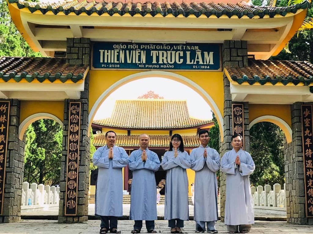 Phật tử mặc áo tràng chắp tay trước cổng tam quan
