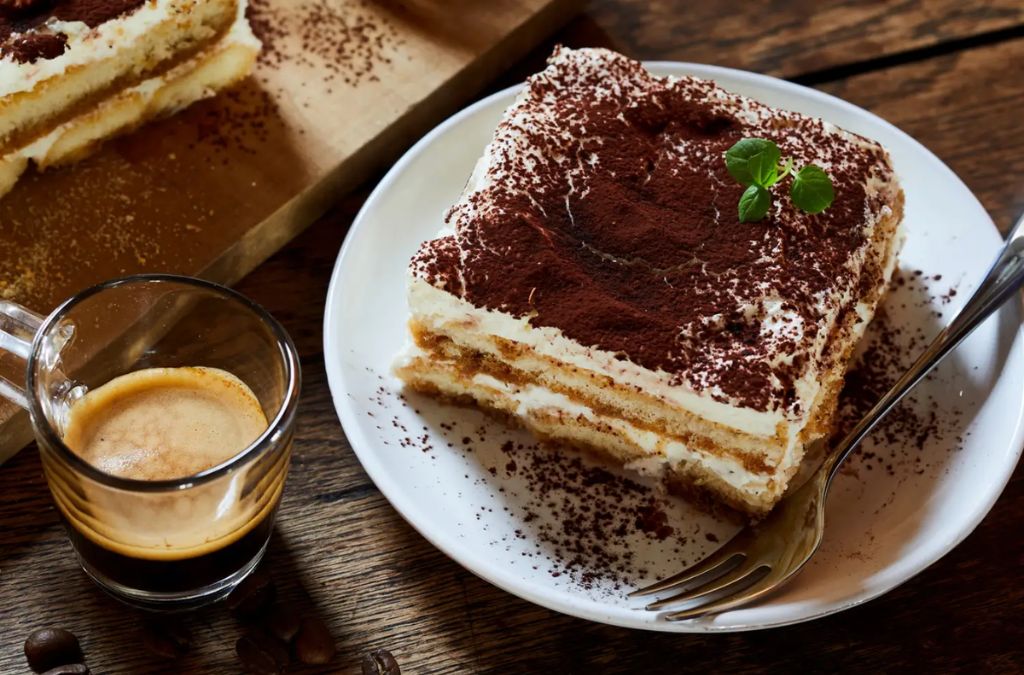 Miếng bánh tiramisu phủ bột cacao dùng cùng một tách espresso
